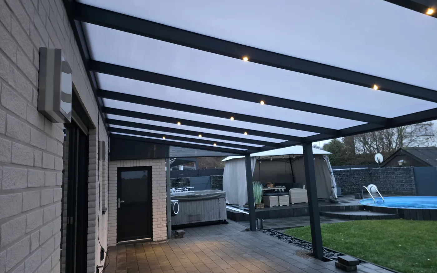 Alu-Terrassendach mit Dacheindeckung, Wandanschluss, LED-Spots und Pfosten gut zu sehen